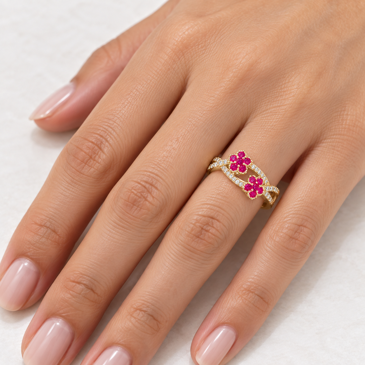 14K solid yellow gold fuchsia CZ floral bypass ring worn naturally on a woman’s hand
