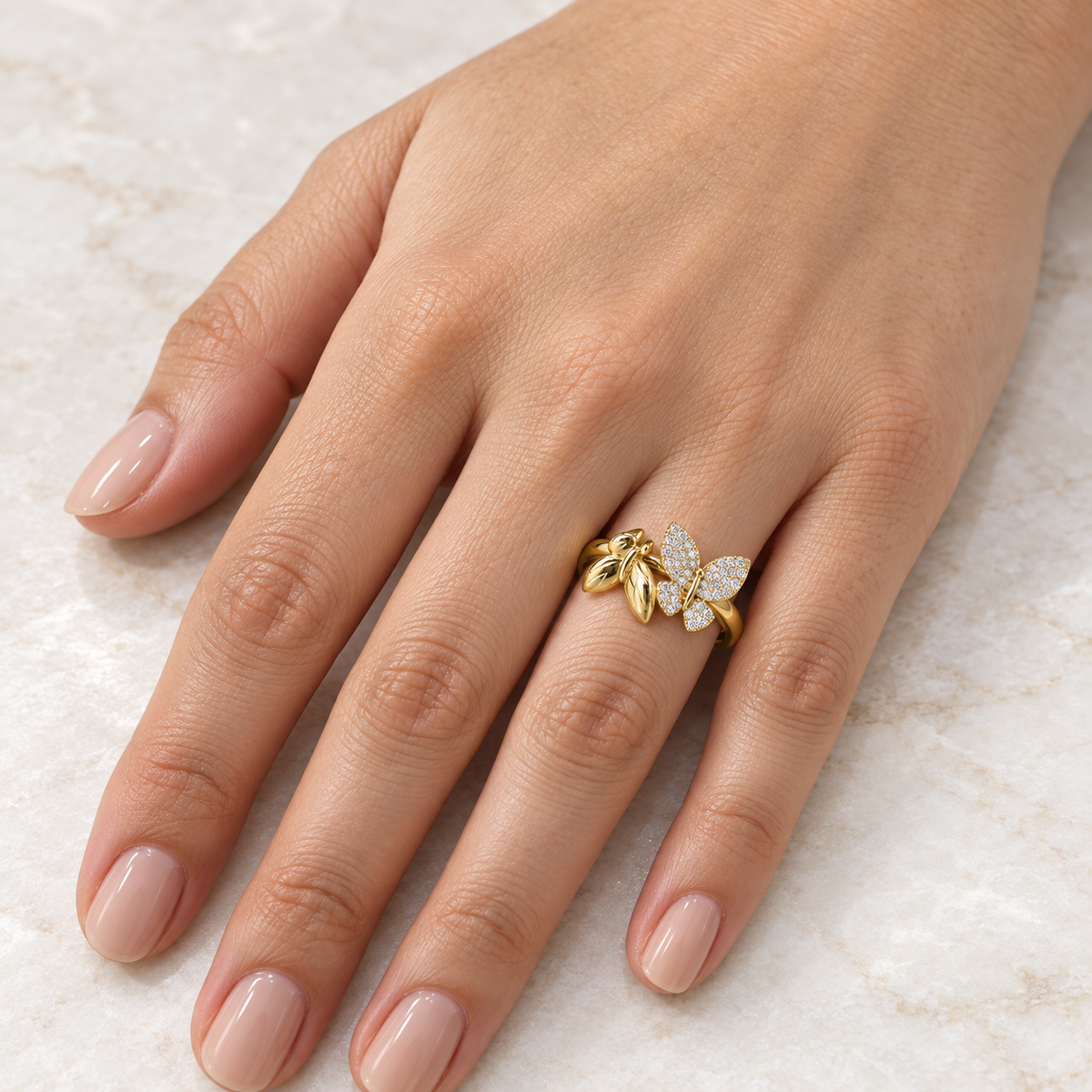     14K solid yellow gold two-butterfly ring with clear cubic zirconias worn on a woman’s hand.