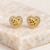 Pair of 13mm 14K solid gold heart nugget stud earrings displayed on a light natural crystal tile