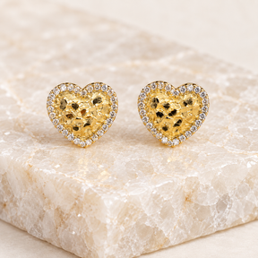 Pair of 13mm 14K solid gold heart nugget stud earrings displayed on a light natural crystal tile