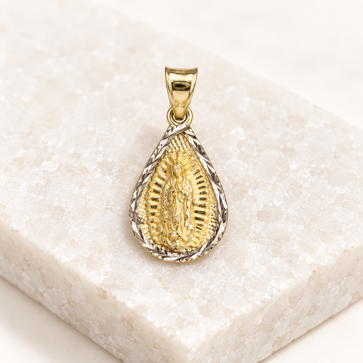 14K solid gold Virgen de Guadalupe teardrop pendant displayed on a white crystalline stone