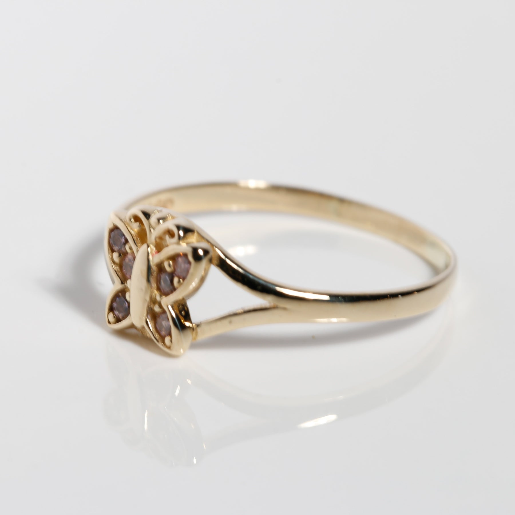 Angled view of butterfly gold ring with pink cubic zirconia accents