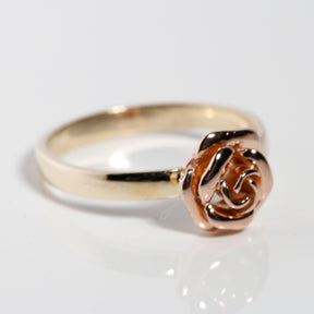 Angled view of solid gold rose flower ring in yellow and rose gold