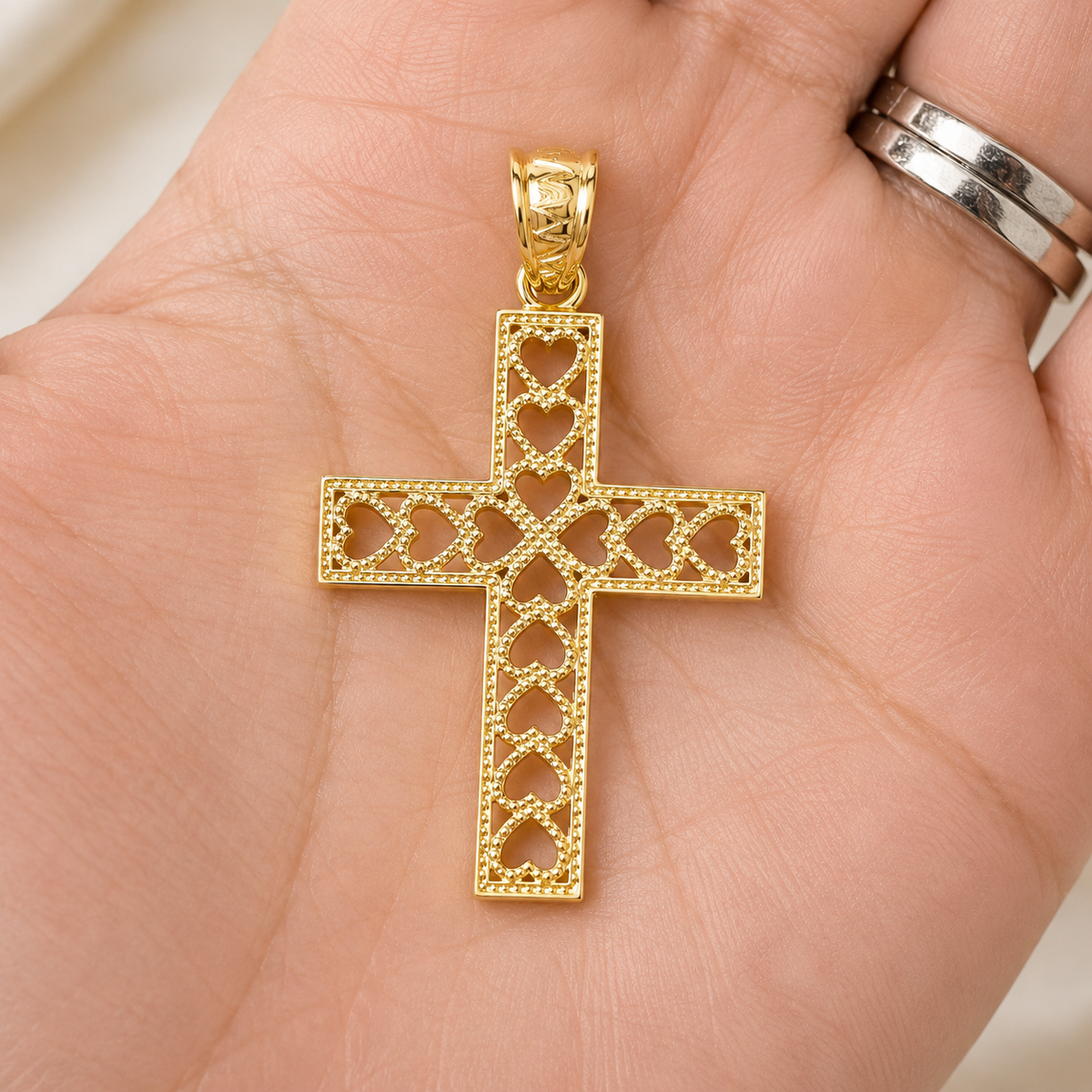 14K solid yellow gold heart cross pendant shown in hand for size reference.